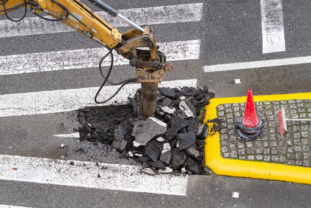 A jackhammer equipment drilling the road pavement.